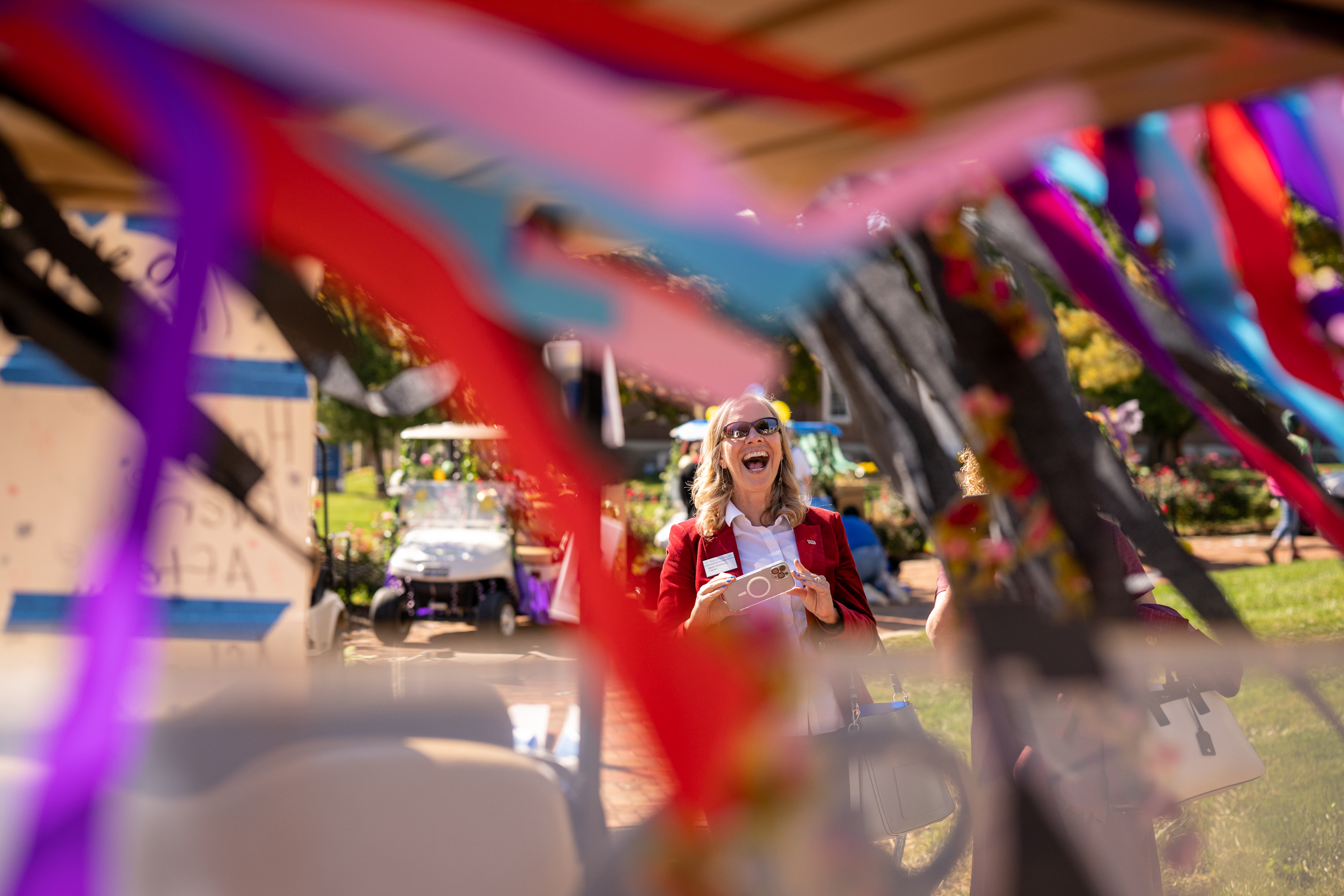 Stacey Robertson is seen laughing through streamers hanging off a decorated golf cart.