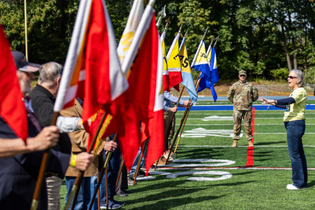 President Robertson talks to PMC alumni who are holding flags from their graduation years.